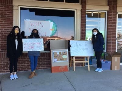 This is a photo of international club members holding signs for the book drive. 